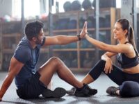 Gym wellness couple high five for success or good exercise and well done gesture for reaching fitness goal. Active trainer and client woman celebrating a great workout, training or exercising session